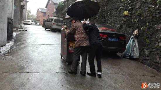 邵阳城管为小摊贩撑伞被网友拍下。 图片来源：红网论坛
