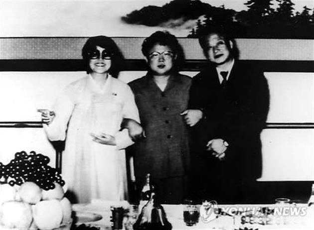 崔银姬(左)和老公申相玉(右)与朝鲜领导人金正日(中)