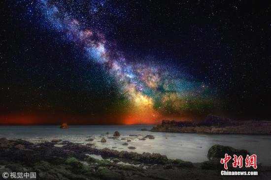 资料图：绚丽的银河及星云与海岸线碰撞出一幅多彩画卷。图片来源：视觉中国