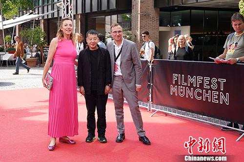 7月3日，中国着名导演贾樟柯在德国出席慕尼黑国际电影节。慕尼黑国际电影节是规模仅次于欧洲三大电影节之一的柏林电影节的德国第二大电影盛会。贾樟柯新片《江湖儿女》将在本次电影节期间举行德国首映。图为贾樟柯(中)与电影节主席Diana Iljine(左)和选片人Bernhard Karl(右)走红毯。中新社记者 彭大伟 摄