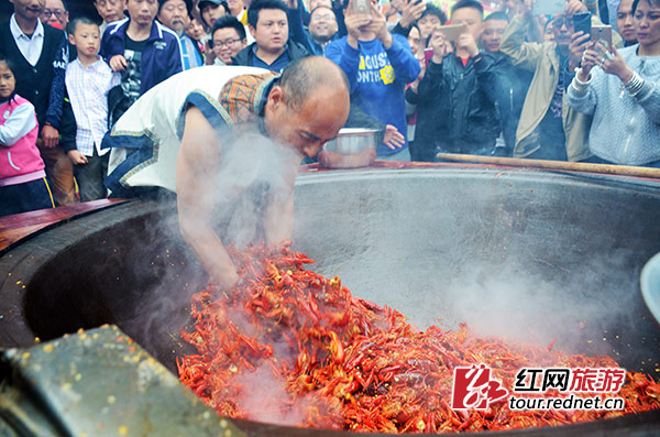 “鬼谷神功”大师唐程刚将手伸进油锅，翻炒龙虾。