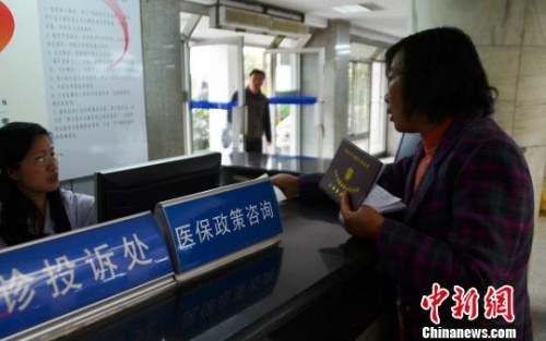 资料图。一名女子在医保政策咨询台前咨询。 
