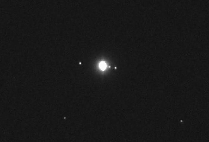 图中显示“奥里西斯- REx”探测器最新拍摄的图像，中心位置是木星，右侧是木卫一和木卫二，左侧是木卫四，木卫三是木星第四大卫星，也出现在这张图像中，但由于运行至